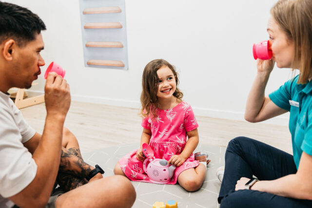 A child with her dad and occupational therapist